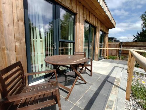 eine Terrasse mit einem Holztisch und Bänken auf einem Gebäude in der Unterkunft The Gallery Lodges in Braunton