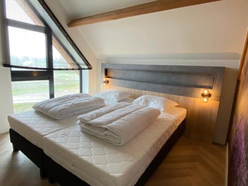 ein Schlafzimmer mit einem Bett mit weißen Laken und Kissen in der Unterkunft Zandbank Villa's in Vrouwenpolder