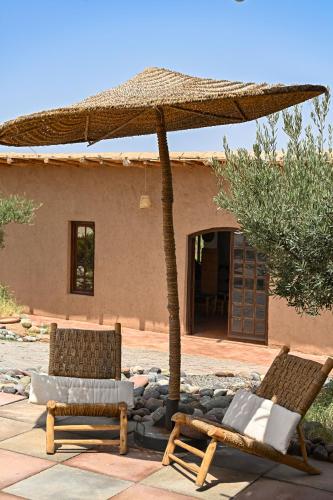 two chairs and an umbrella in front of a house at Le Parc des Oliviers in Marrakech