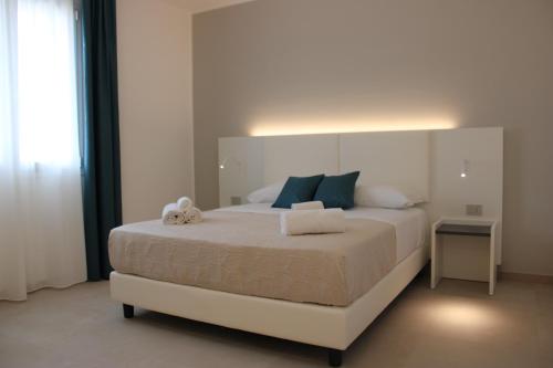 a bedroom with a large white bed with blue pillows at Coral Sand bed and breakfast in San Vito lo Capo