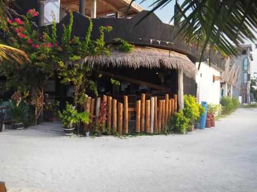 a building with a straw roof with flowers and plants at Club Kaafu Maldives in Dhiffushi