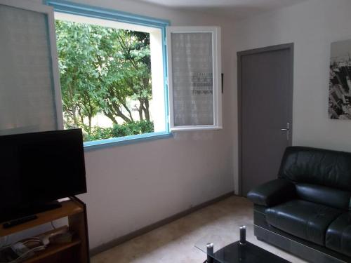 - un salon avec un canapé noir et une fenêtre dans l'établissement Kerleuquer Ty Nevez, à Plobannalec-Lesconil