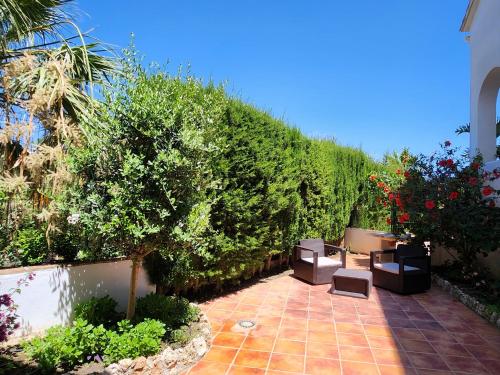 a patio with two chairs and a hedge at DELUXE Studio ATHOS 50 MP Garden patio BENALMADENA Golf & Beach in Benalmádena
