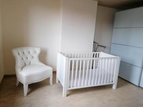 cuna blanca y silla en una habitación en Maison Miest, en Watou