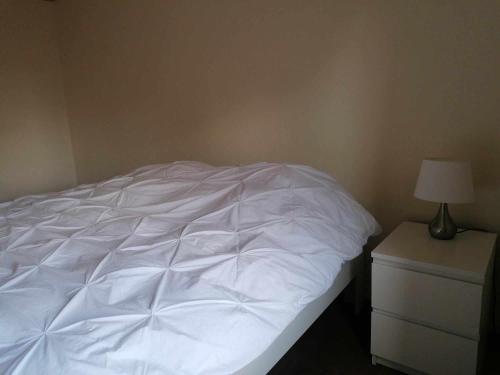 a bed with white sheets and a lamp on a nightstand at Maison Miest in Watou
