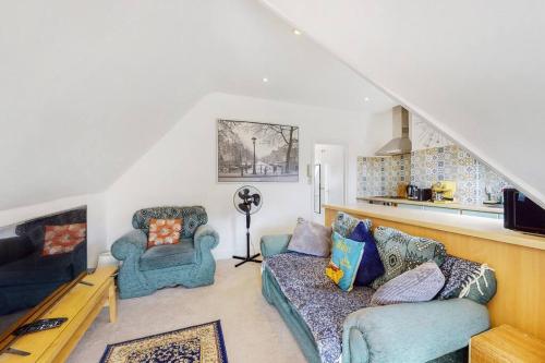 a living room with two blue couches and a kitchen at Homely 1 BR apartment with parking in Streatham in London