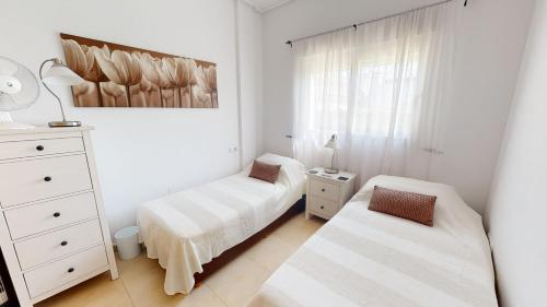 a white bedroom with two beds and a dresser at Casa Quisqueya - A Murcia Holiday Rentals Property in Roldán