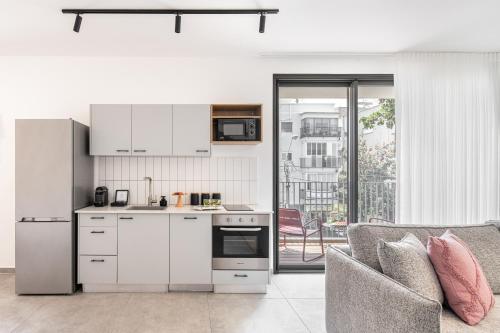 a kitchen with white cabinets and a couch in a living room at Mate GEORGE - By HOMY in Tel Aviv