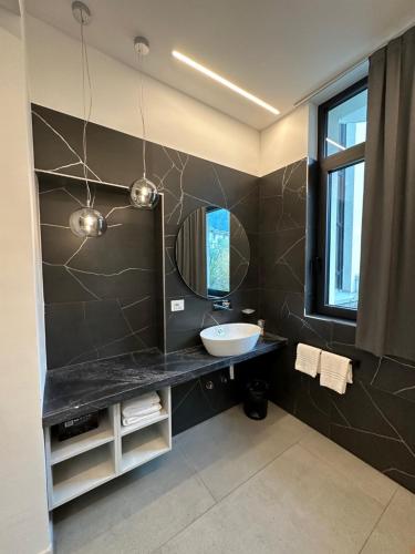 La salle de bains est pourvue d'un lavabo et d'un miroir. dans l'établissement Athos Hotel, à Riva del Garda