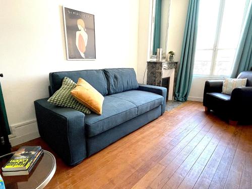 ein Wohnzimmer mit einem blauen Sofa und einem Tisch in der Unterkunft Appartement cosy et lumineux centre-ville #4 in Dreux