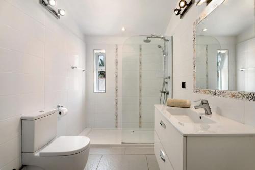 a white bathroom with a toilet and a sink at Villa Malpas in San Miguel de Abona