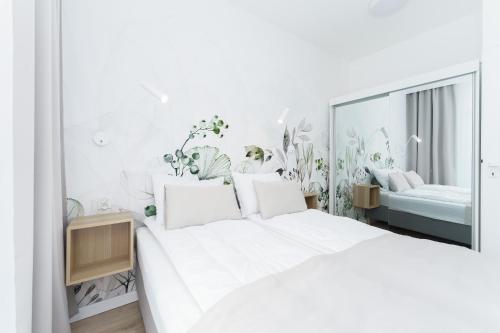 um quarto branco com uma grande cama branca e plantas em Apartament Perłowy Ku Morzu by HolidaySun em Sianozety