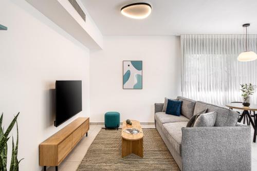 a living room with a couch and a tv at Mate GEORGE - By HOMY in Tel Aviv