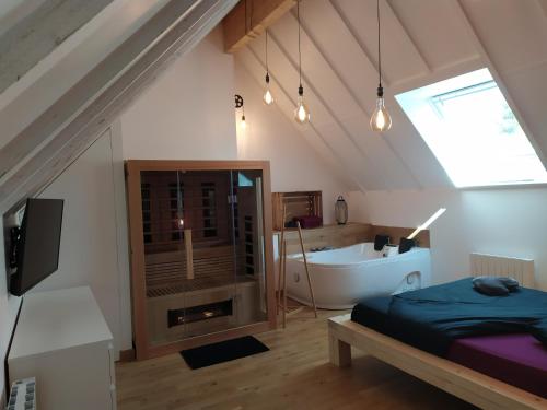 a attic bedroom with a bed and a bath tub at Calme et Volupté in Maxilly-sur-Saône