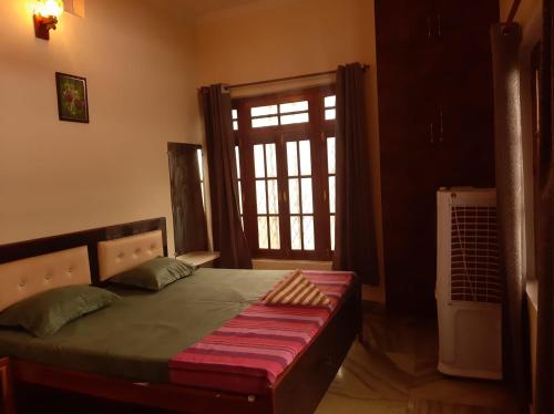 1 dormitorio con 1 cama, ventana y puerta en PAARIJAAT Homestay & Guesthouse en Ayodhya