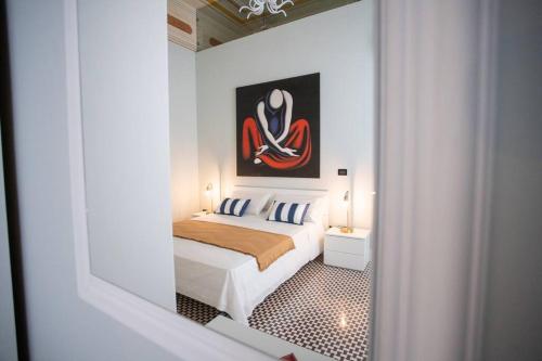 1 dormitorio con 1 cama y una pintura en la pared en Palazzo Ginevra, en Gallico Marina