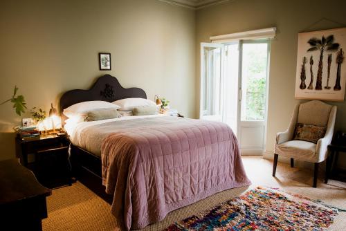 a bedroom with a large bed and a chair at Dorp Hotel in Cape Town