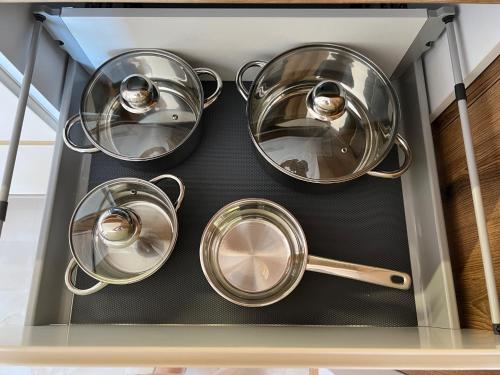 four pots and pans on a shelf in a kitchen at Luxe Living Stara Pazova in Stara Pazova