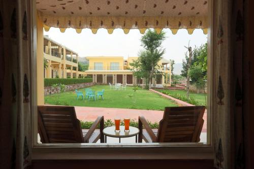 an open window with a table and chairs and a yard at Ratan Villas Sariska in Alwar