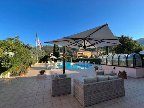 a patio with couches and an umbrella next to a pool at Arthotel Gabbiano Azzurro Due in Marciana Marina