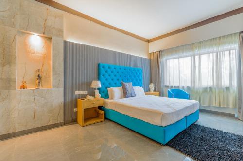 a bedroom with a blue bed and a window at Hotel Pal Heights in Bhubaneshwar