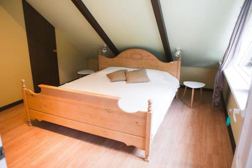 a bedroom with a wooden bed with white sheets at Aizpuri West View in Nīca