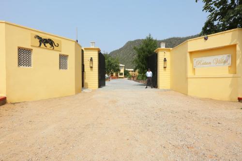 a man walking down a dirt road between two yellow buildings at Ratan Villas Sariska in Alwar