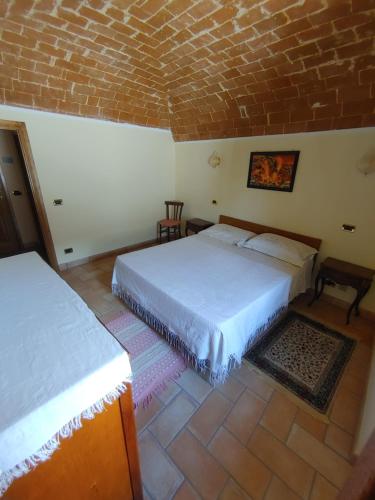 a bedroom with two beds and a brick wall at Casa Collarano in San Demetrio neʼ Vestini