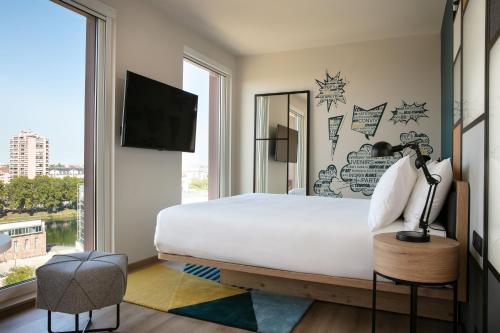 sypialnia z dużym białym łóżkiem i oknem w obiekcie Aloft Strasbourg Etoile w Strasburgu
