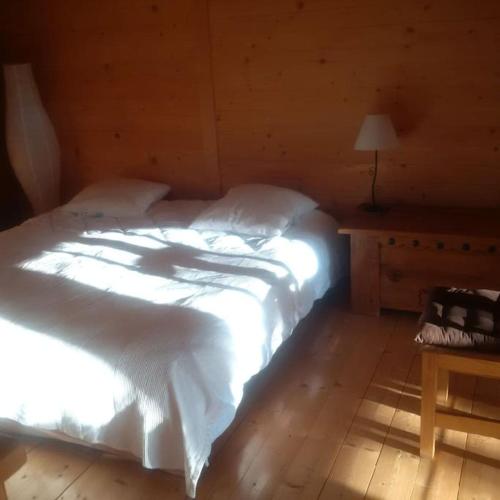 a bedroom with a bed with white sheets and a table at LA PLAGNE MONTALBERT Chalet - fitness - wifi in Montgésin