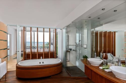 a bathroom with a large tub and two sinks at Hotel Palafitte in Neuchâtel