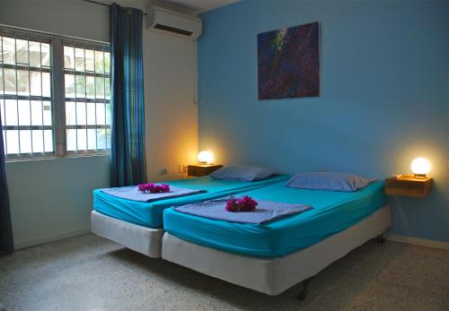 Caribbean Flower Apartments في فيليمستاد: غرفة نوم زرقاء مع سريرين مع زهور أرجوانية عليها