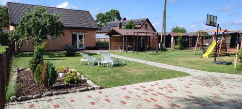 een achtertuin met een speeltuin met stoelen en een glijbaan bij Kaltenes Liepziedi in Roja