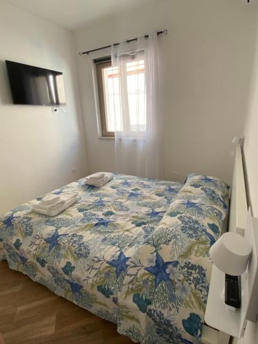 Schlafzimmer mit einem Bett mit einer blauen und weißen Bettdecke in der Unterkunft Casa Gina e Pietro in Ustica
