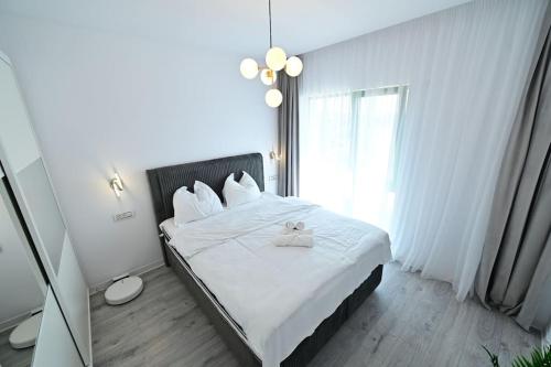 a bedroom with a bed with white sheets and a window at FLH - The Lake Home - Apt 33 in Sibiu