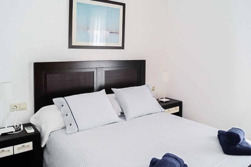 une chambre avec un grand lit blanc avec deux tables de nuit dans l'établissement Villa Opal, à Cala'n Bosch