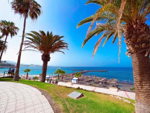 Blick auf das Meer von einem Park mit Palmen in der Unterkunft First line apartment in El Beril Playa del Duque PD1 in Adeje