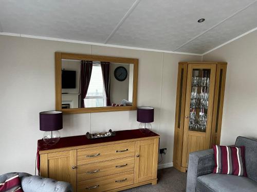 Pebble Lodge في Tydd Saint Giles: غرفة معيشة مع خزانة ملابس ومرآة