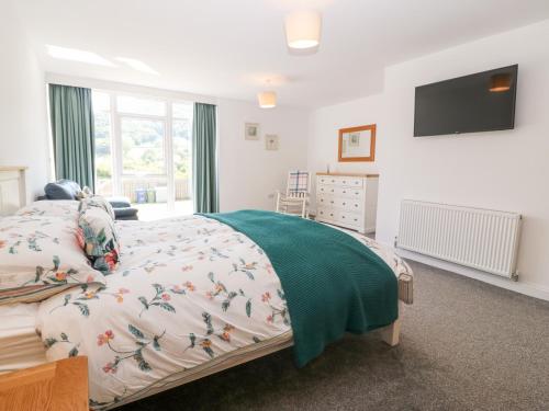 a bedroom with a bed and a flat screen tv at 3 Pensyflog Barns in Porthmadog