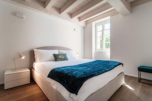 a white bedroom with a large bed and a window at Il Balcone sul Lago by Quokka 360 - historic lakeside flat in Morcote in Morcote