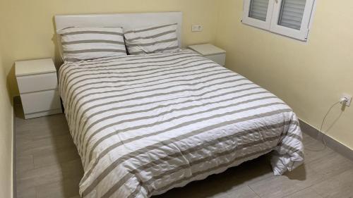 een bed met een gestreepte deken in een slaapkamer bij Casa Roquetas in Roquetas de Mar