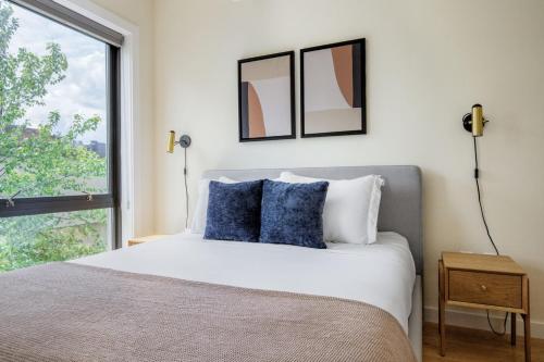 um quarto com uma cama com almofadas azuis e uma janela em Fenway 1br w gym wd nr dining shops BOS-872 em Boston