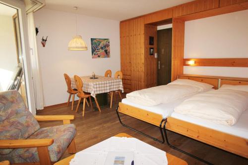 Cette chambre comprend deux lits et une table avec une table. dans l'établissement Residenza Lagrev 1 Zimmerwohnung Nr 103 - Typ 12B - 1 Etage - Süd, à Sils-Maria