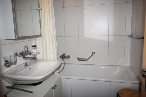 bagno con lavandino e vasca di Residenza Lagrev 1 1 2 Zimmerwohnung Nr 121 - Typ 15A - 1 Etage - N W a Sils Maria
