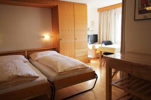 ein Schlafzimmer mit einem Bett und einem Schreibtisch. in der Unterkunft Residenza Lagrev 1 Zimmerwohnung Nr 227 - Typ 11B - 2 Etage - Ost in Sils Maria