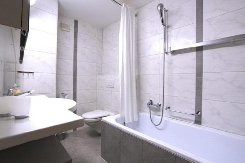 ein Badezimmer mit einer Badewanne, einem WC und einem Waschbecken in der Unterkunft Residenza Lagrev 1 Zimmerwohnung Nr 228 - Typ 11A - 2 Etage - Ost in Sils Maria