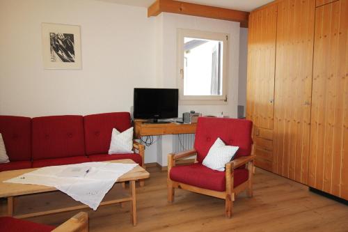 sala de estar con 2 sillas rojas y escritorio en Residenza Lagrev 2 Zimmerwohnung Nr 112 - Typ 21B - 1 Etage - Süd, en Sils-Maria