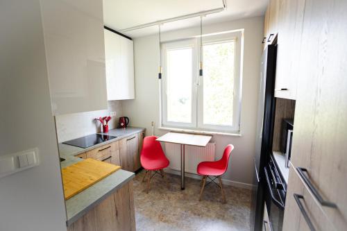 a kitchen with two red chairs and a table at Sowi Loft in Hajnówka
