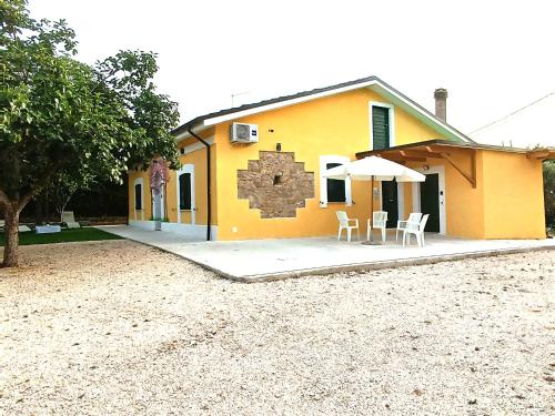 a yellow house with two chairs and an umbrella at La Casa Di Lucia in San Vito Chietino