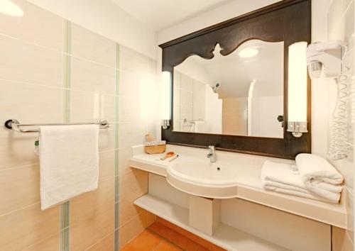a white bathroom with a sink and a mirror at Sur la Plage @ Pierre & Vacances in Sainte-Anne